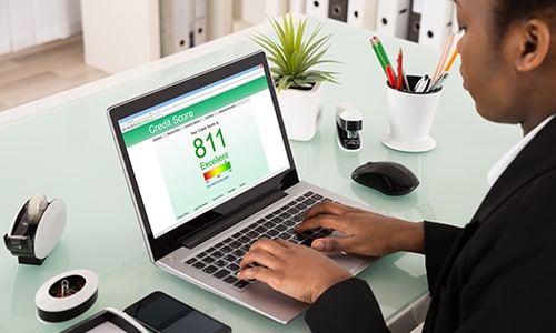 Person sitting at desk checking their credit score on a laptop.